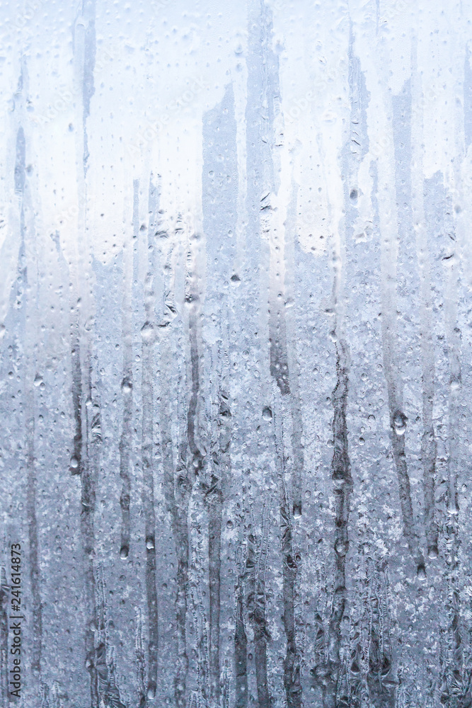 The frozen drops on the patterned frosty winter window