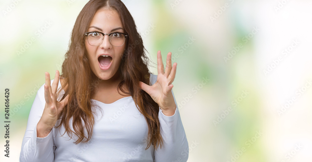 Beautiful plus size young woman over isolated background crazy and mad shouting and yelling with aggressive expression and arms raised. Frustration concept. Beautiful plus size young woman over isolated background crazy and mad shouting and yelling with aggressive expression and arms raised. Frustration concept.