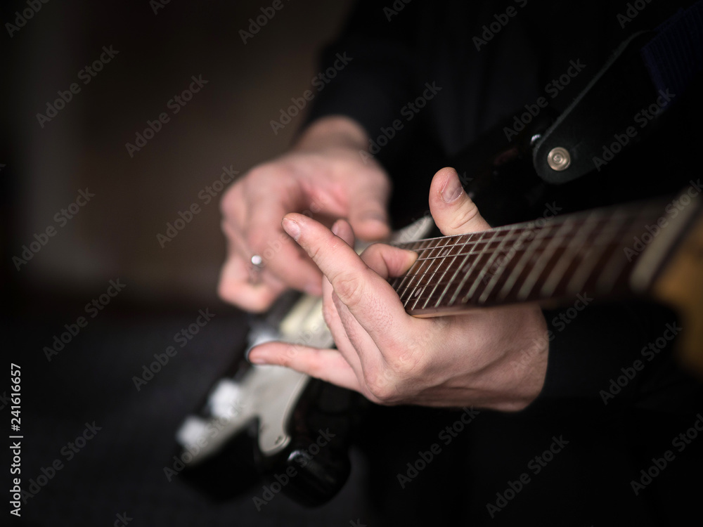 Male hands playing on electric guitar, close up, selected focus