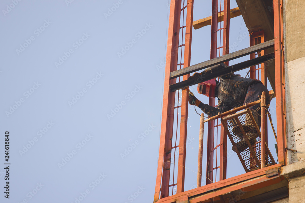 Welder work at a height in the building under construction. Welder work at a height in the building under construction.