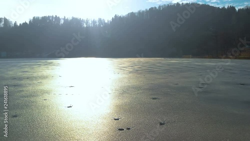 Aerial view of a frozen little Lake in Switzerland at a sunny winter Day