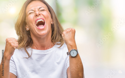 Middle age senior hispanic woman over isolated background very happy and excited doing winner gesture with arms raised, smiling and screaming for success. Celebration concept.