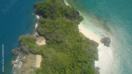 Aerial view Matukad island with sand beach and turquoise water in blue lagoon among coral reefs, Caramoan Islands, Philippines. Landscape with sea, tropical beach.