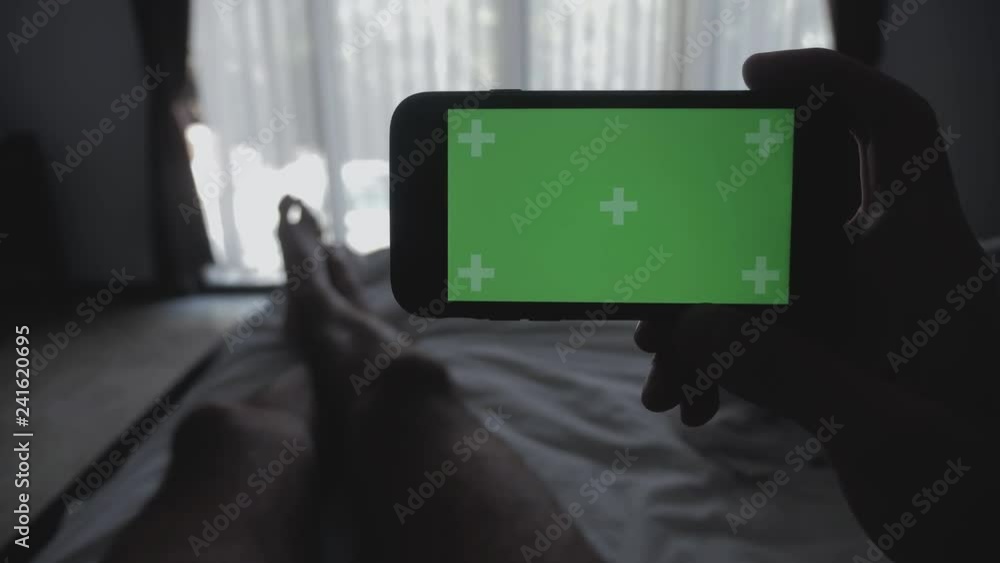 Close up Young Man laying on the bed holding smartphone green screen