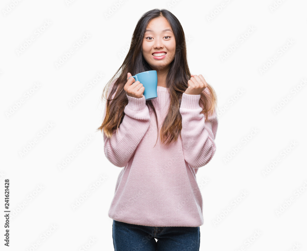 Young asian woman drinking coffee over isolated background screaming proud and celebrating victory and success very excited, cheering emotion
