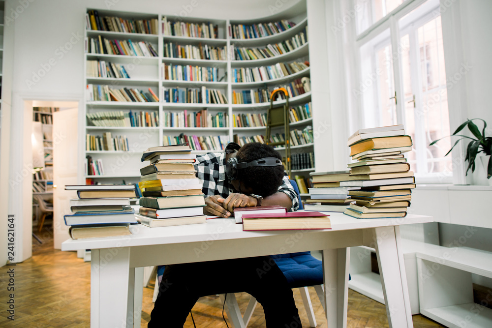 An African student sleeping at a desk in the library An African student sleeping at a desk in the library