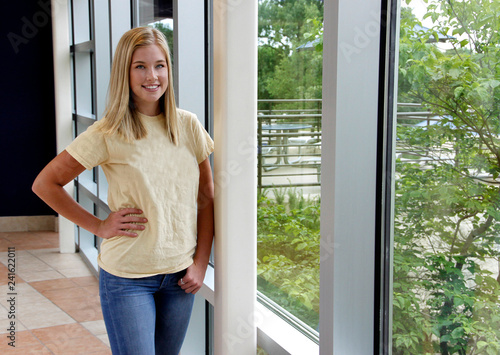Female college student standing next to wall of windows