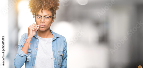 Beautiful young african american woman wearing glasses over isolated background mouth and lips shut as zip with fingers. Secret and silent, taboo talking