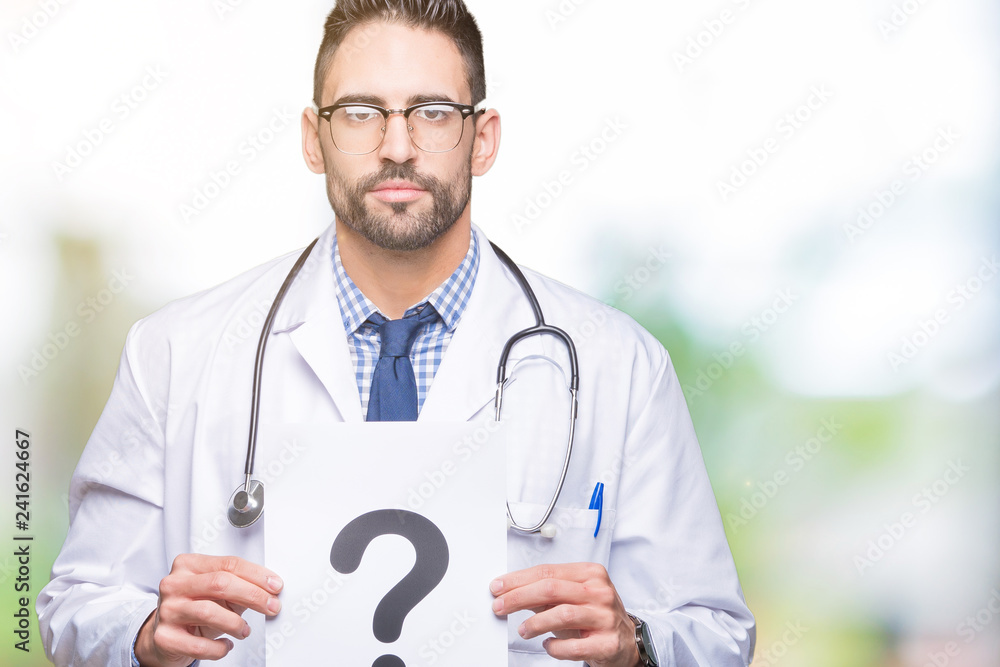 Handsome young doctor man holding paper with question mark over isolated background with a confident expression on smart face thinking serious Handsome young doctor man holding paper with question mark over isolated background with a confident expression on smart face thinking serious