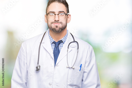 Handsome young doctor man over isolated background puffing cheeks with funny face. Mouth inflated with air, crazy expression.