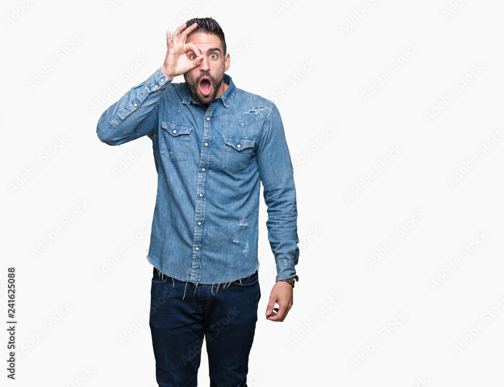 Young handsome man over isolated background doing ok gesture shocked with surprised face, eye looking through fingers. Unbelieving expression. Young handsome man over isolated background doing ok gesture shocked with surprised face, eye looking through fingers. Unbelieving expression.