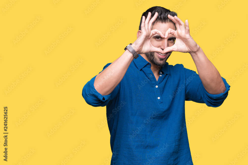 Young handsome man over isolated background Doing heart shape with hand and fingers smiling looking through sign Young handsome man over isolated background Doing heart shape with hand and fingers smiling looking through sign