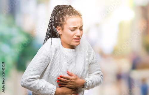 Young braided hair african american girl wearing winter sweater over isolated background with hand on stomach because nausea, painful disease feeling unwell. Ache concept.