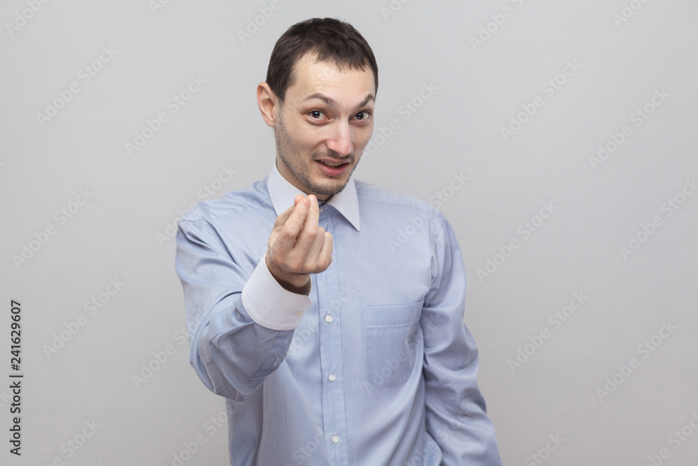 You need to pay. Portrait of handsome funny bristle businessman in classic light blue shirt standing with money gesture and looking at camera. indoor studio shot, isolated on grey background copyspace You need to pay. Portrait of handsome funny bristle businessman in classic light blue shirt standing with money gesture and looking at camera. indoor studio shot, isolated on grey background copyspace