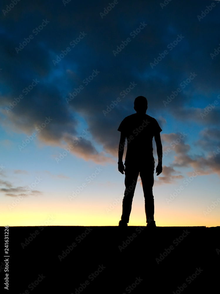 Homme se tenant avec détermination face au coucher de soleil