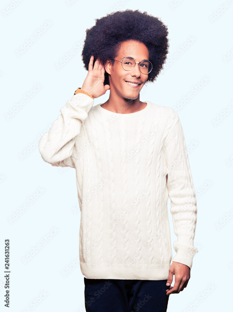 Young african american man with afro hair wearing glasses smiling with hand over ear listening an hearing to rumor or gossip. Deafness concept. Young african american man with afro hair wearing glasses smiling with hand over ear listening an hearing to rumor or gossip. Deafness concept.