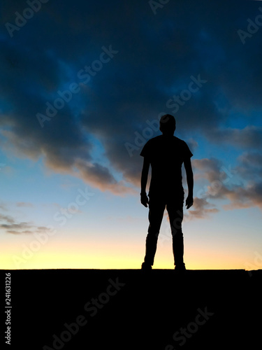 Homme se tenant avec détermination face au coucher de soleil