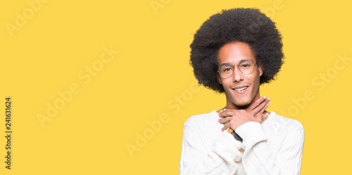Young african american man with afro hair wearing glasses shouting and suffocate because painful strangle. Health problem. Asphyxiate and suicide concept.