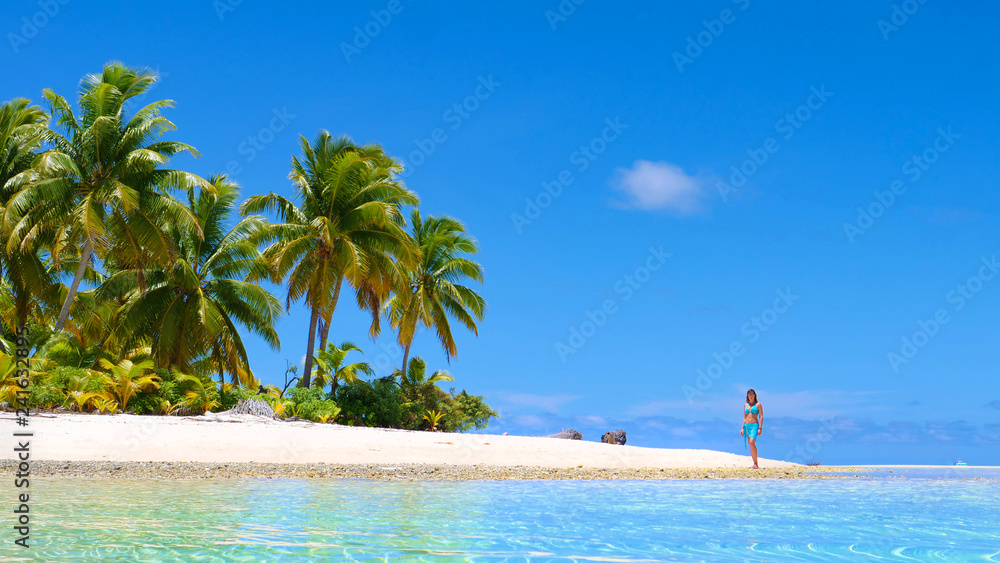 Obraz premium LOW ANGLE: Young girl in bikini going for a scenic walk down the sandy beach.