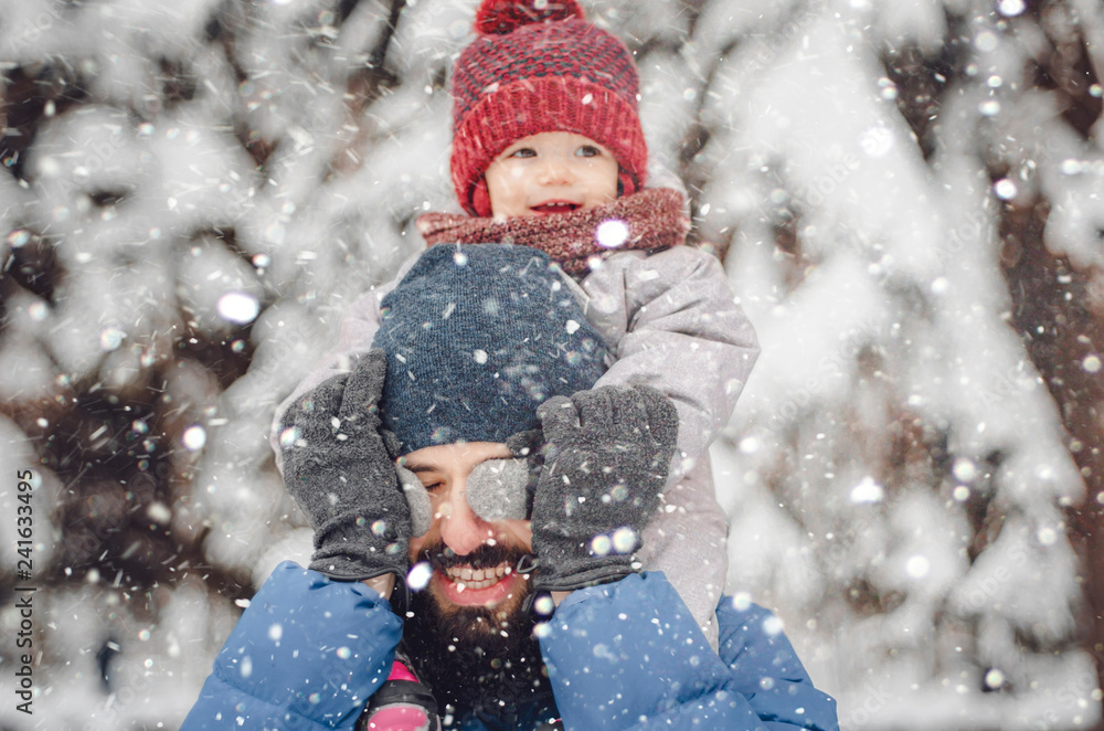 Portrait of a happy man piggybacking his cheerful child. happy father and baby son having fun under winter snow, holiday season. Portrait of a happy man piggybacking his cheerful child. happy father and baby son having fun under winter snow, holiday season.
