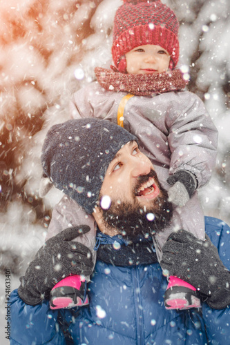 happy father and baby son having fun under sunny winter snow, holiday season.