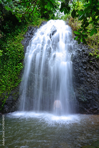 Canvas Print View of the silhouette of a man bathing under a cascading waterfall in Tahiti, F