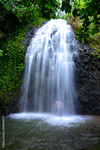 View of the silhouette of a man bathing under a cascading waterfall in Tahiti  French Polynesia