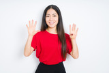 Beautiful brunette woman wearing red t-shirt over isolated background showing and pointing up with fingers number nine while smiling confident and happy.