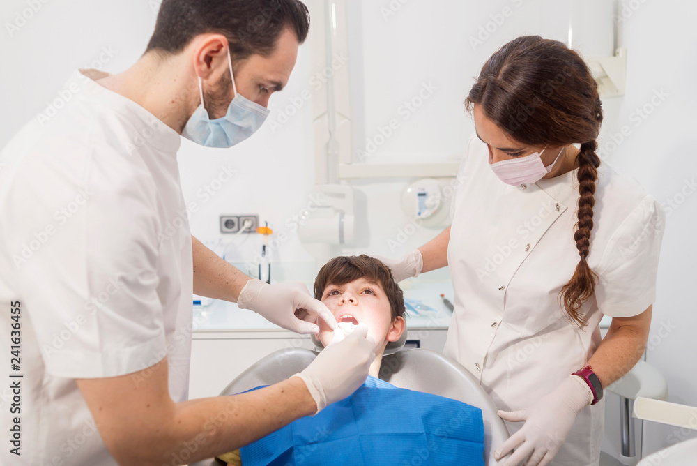 Dentist examining patient's teeth by assistant in medical clinic Dentist examining patient's teeth by assistant in medical clinic
