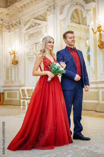 a beautiful woman in a red dress stands with a man, bride and groom, happy newlyweds.