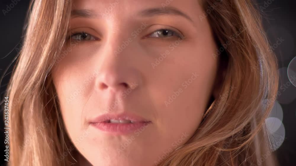 Closeup portrait of beautiful glowing caucasian female face turning and looking straght at camera with night lights background Closeup portrait of beautiful glowing caucasian female face turning and looking straght at camera with night lights background