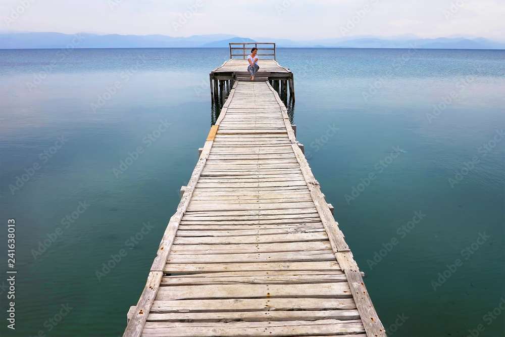 Obraz premium woman sits on the pier, Corfu Greece