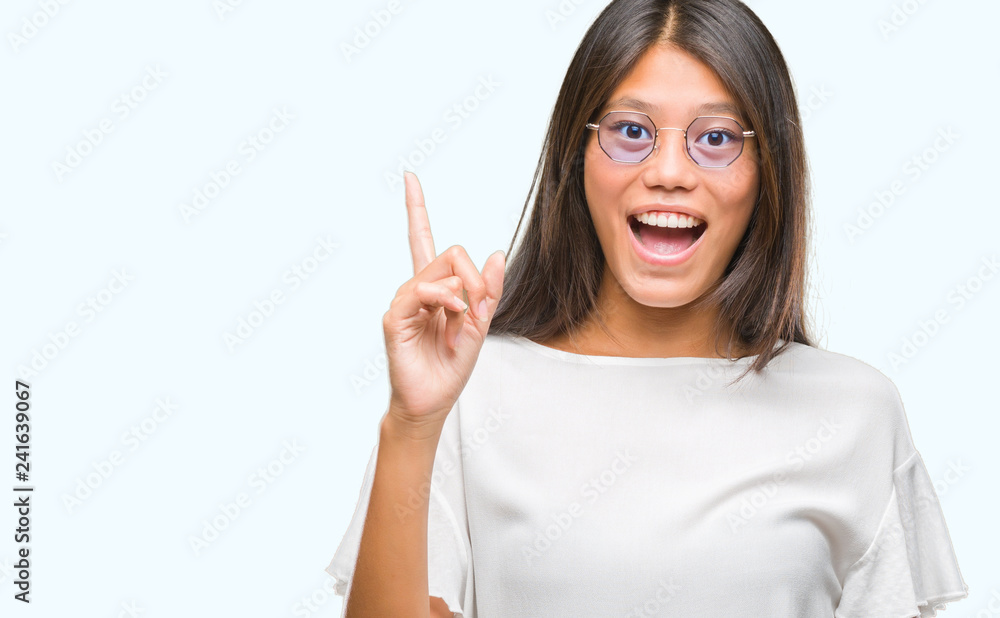 Young asian woman wearing glasses over isolated background pointing finger up with successful idea. Exited and happy. Number one. Young asian woman wearing glasses over isolated background pointing finger up with successful idea. Exited and happy. Number one.