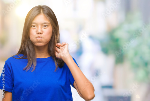 Young asian woman over isolated background puffing cheeks with funny face. Mouth inflated with air, crazy expression.