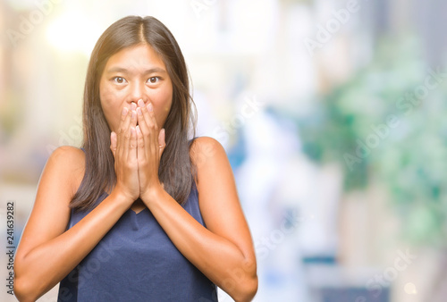Young asian woman over isolated background shocked covering mouth with hands for mistake. Secret concept.