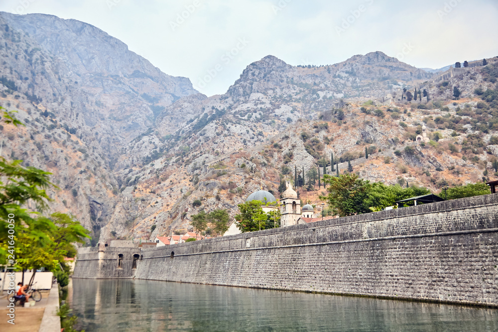 Stone wall of old fortress of Kotor, Montenegro. Church and mountains in the background