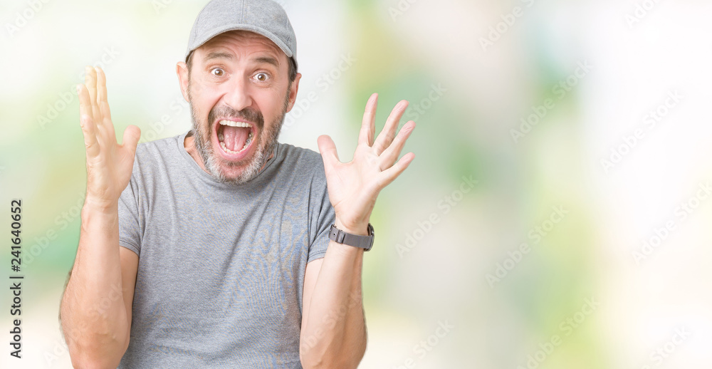 Handsome middle age hoary senior man wearing sport cap over isolated background celebrating crazy and amazed for success with arms raised and open eyes screaming excited. Winner concept Handsome middle age hoary senior man wearing sport cap over isolated background celebrating crazy and amazed for success with arms raised and open eyes screaming excited. Winner concept