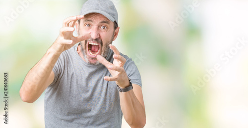 Handsome middle age hoary senior man wearing sport cap over isolated background Shouting frustrated with rage, hands trying to strangle, yelling mad