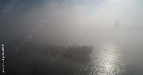 A huge barge on the river Dnipro in the morning fog with a visible silhouette of the buildings and city in the background (shot from the air) in 4K 7