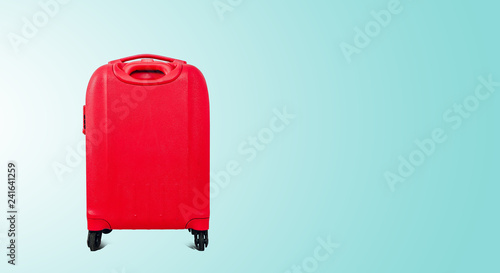 A red travel suitcase on wheels, isolated on a green pastel background. Travel concept, packing up before departure. Preparing for travel, going on vacation, break, rest.