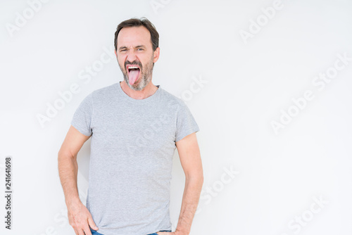 Handsome senior man over isolated background sticking tongue out happy with funny expression. Emotion concept.