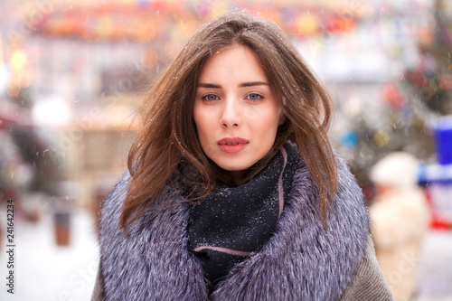 Young brunette woman in a gray coat with a fur collar