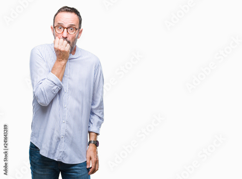 Middle age hoary senior man wearing glasses over isolated background looking stressed and nervous with hands on mouth biting nails. Anxiety problem. © Krakenimages.com