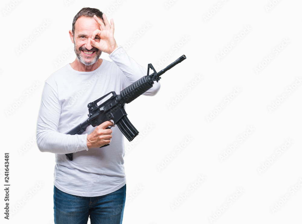 Middle age senior hoary criminal man holding gun weapon over isolated background with happy face smiling doing ok sign with hand on eye looking through fingers Middle age senior hoary criminal man holding gun weapon over isolated background with happy face smiling doing ok sign with hand on eye looking through fingers