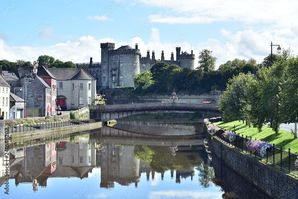 View of calm river Nore with bridge and stone Kilkenny Castle in background.
