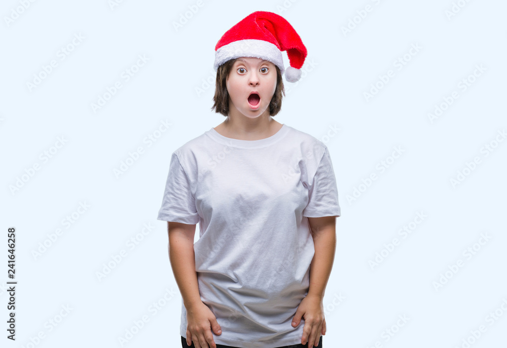 Young adult woman with down syndrome wearing christmas hat over isolated background afraid and shocked with surprise expression, fear and excited face. Young adult woman with down syndrome wearing christmas hat over isolated background afraid and shocked with surprise expression, fear and excited face.