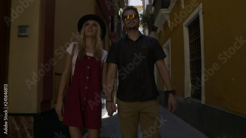 Tracking shot of approaching tourist couple admiring architecture in city / Seville, Sevilla, Spain