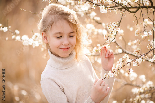 Blonde girl in the blossom garden. Spring background with white flower