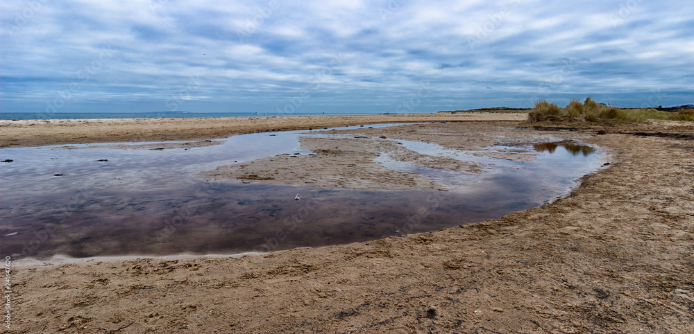 Studland beach on a January day with dramatic cloudy sky and reflection in water. Panoramic landscape. Studland beach on a January day with dramatic cloudy sky and reflection in water. Panoramic landscape.