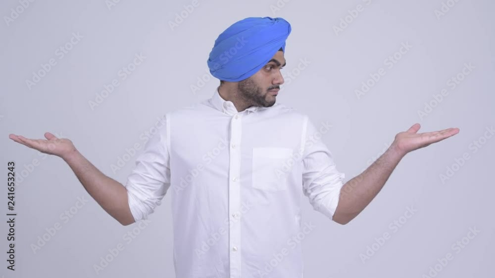 Young bearded Indian Sikh man comparing something Young bearded Indian Sikh man comparing something